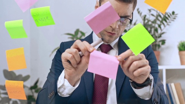 handsome, attentive businessman writing on sticky notes - Footage, Video