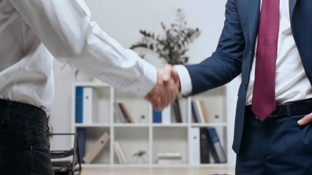 partial view of two businessmen shaking hands while standing in office - Footage, Video