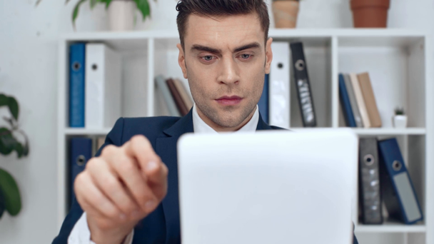 valikoiva painopiste komea, vakava liikemies käyttäen digitaalinen tabletti toimistossa
 - Materiaali, video