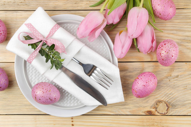 Πάσχα. Ρύθμιση πίνακα Πάσχας. Ροζ Πασχαλινά αυγά και λουλούδια τουλίπες σε ένα φυσικό ξύλινο τραπέζι. Καλό Πάσχα. διακοπές. το top view - Φωτογραφία, εικόνα