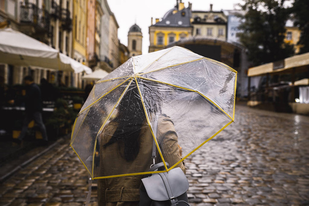 γυναίκα που περπατά με διάφανη ομπρέλα κάτω από βροχή - Φωτογραφία, εικόνα
