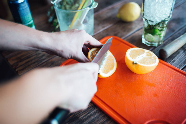 Barman prepares fruit alcohol cocktail based on lime, mint, oran - Foto, Bild