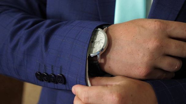 Biznes człowiek stawia na zegarek i prostuje jego rękaw kurtki, szykując się do pracy wcześnie rano. Styl uroczysty Smoking dla mężczyzn. Pomysłem. Szczelnie-do góry - Zdjęcie, obraz