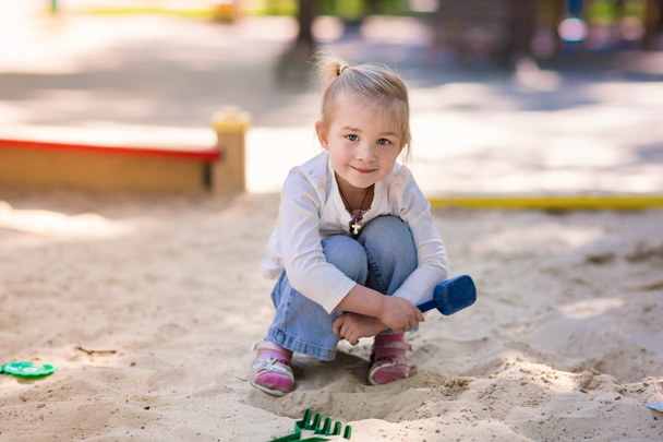Happy little girl playing in a sendbox - Фото, зображення