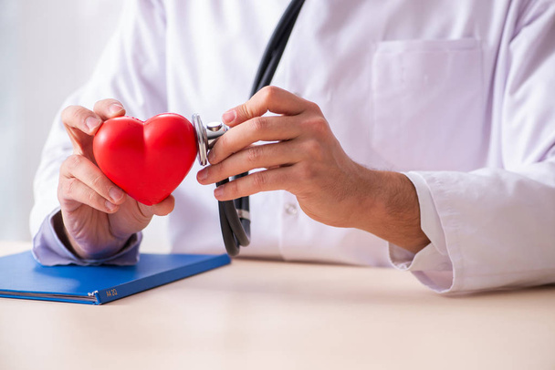 Male doctor cardiologist holding heart model  - Фото, изображение