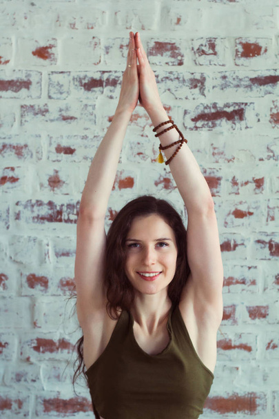 happy smiling beautiful caucasian woman practising yoga agains brick wall in yoga class - Foto, immagini