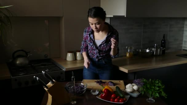 Mutfakta çalışan güzel esmer. Kadın lahana çalışır, salata üzerine yağ dökün ve tuz. Vejetaryen ve sağlıklı yaşam tarzı. 4k 2160p 25fps UHD video. - Video, Çekim