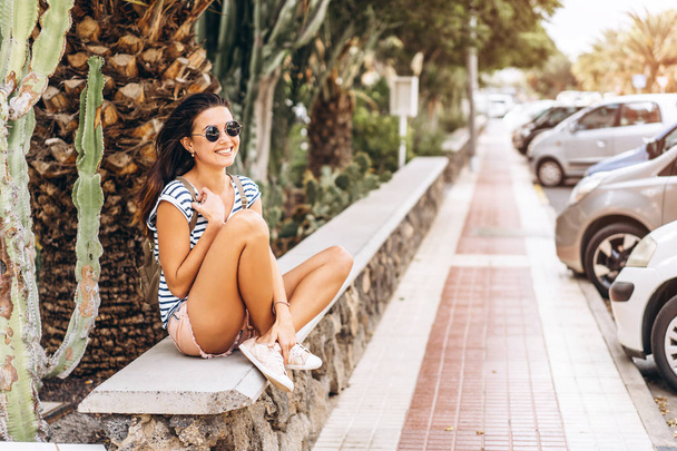 Pretty brunette tourist girl sitting outdoor on the street. - Foto, imagen