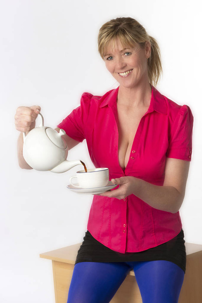 Південній Англії Великобританії. Circa 2018. Приваблива жінка, що носить виявлення червоній сорочці розливу чашку чаю - Фото, зображення