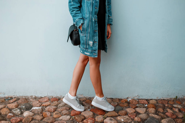 Beautiful female legs with stylish sneakers near blue wall. Fash - Foto, Bild