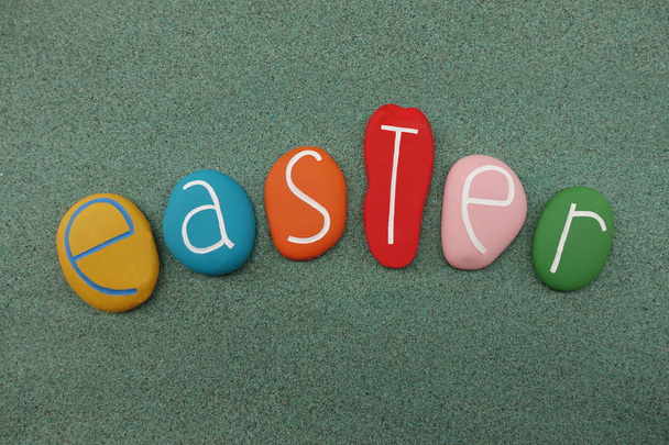 Velikonoce, neděle vzkříšení, svátek oslavující vzkříšení Ježíše s kompozit několika barevných kamenů přes zelený písek - Fotografie, Obrázek
