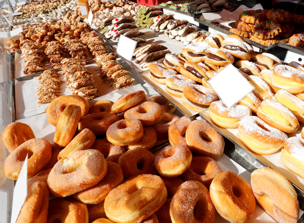много жареных пончиков и больше выпечки с сахаром на продажу в Кио
 - Фото, изображение