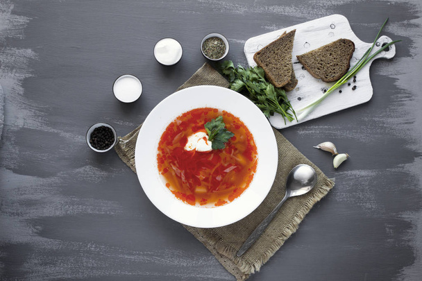 Traditional Ukrainian Russian borsch with sour cream and white beans on a dark background. Red vegetable beetroot soup. - Photo, Image
