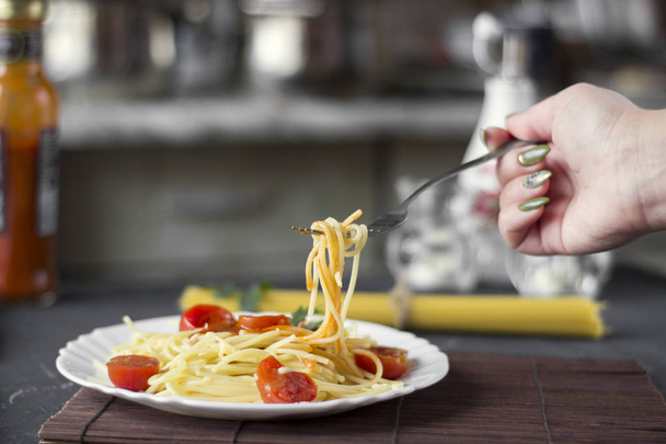 Makaron spaghetti w sosie pomidorowym z serem i pietruszką, kobiecej dłoni. - Zdjęcie, obraz