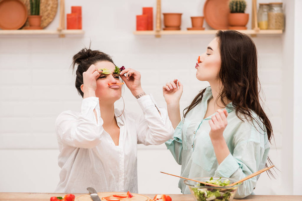 Happy lesbian couple with vegetable in kitchen. - Zdjęcie, obraz