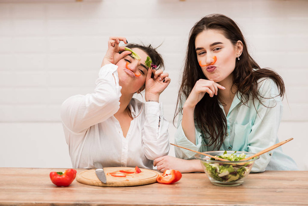 Dvě dívky se bavit s listy salátu jako obočí - Fotografie, Obrázek