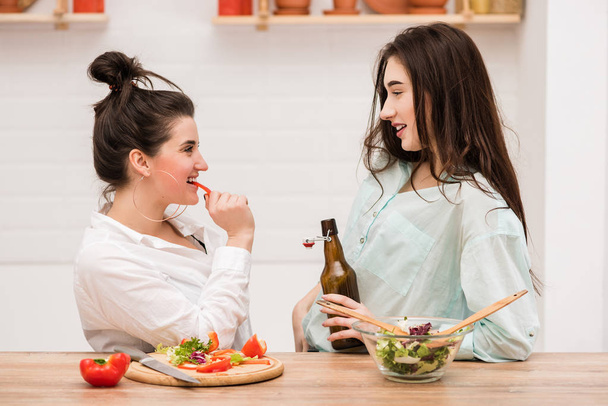 Две молодые женщины делают салат на кухне
 - Фото, изображение