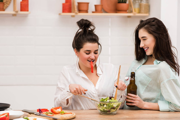 Two happy girls cooking fresh salad together. - Photo, Image