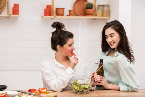 Дві молоді жінки готують салат на кухні
. - Фото, зображення
