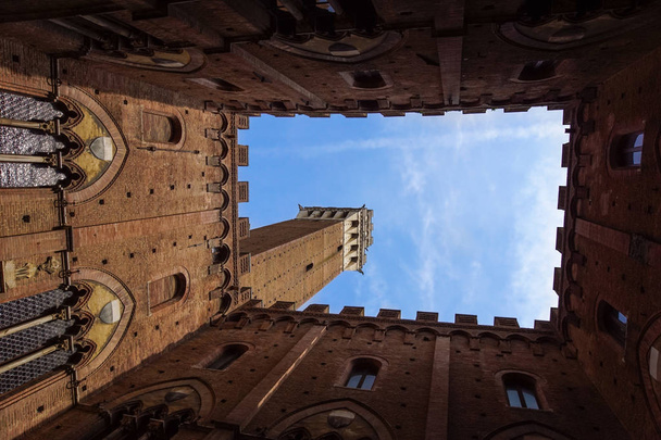 Uitzicht vanaf de binnenplaats van het stadhuis Siena Palazzo Pubblico naar Mangia toren Torre del Mangia en blauw winter sky, Toscane, Italië - Foto, afbeelding