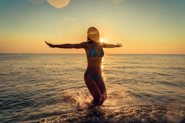 幸せな女が海にジャンプします。屋外の楽しみを持っている人。夏休みと健康的なライフ スタイルのコンセプト. - 写真・画像