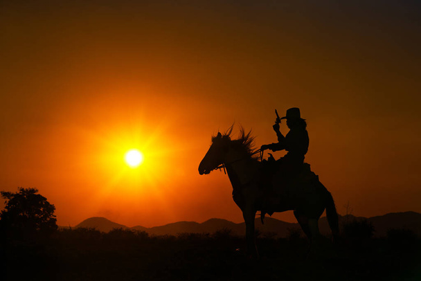 σιλουέτα καουμπόη ιππασίας ένα άλογο στην Ανατολή του ηλίου - Φωτογραφία, εικόνα