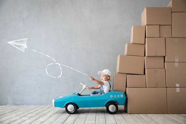 Happy child playing into new home. Kid driving toy car. Moving day concept - Fotoğraf, Görsel