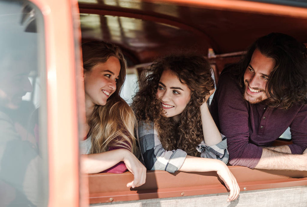 A group of young friends on a roadtrip through countryside, looking out of window. - Foto, Bild