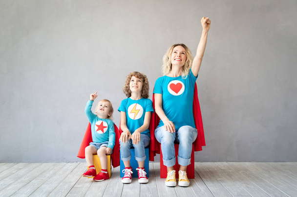 Family of superheroes playing at home. Mother, daughter and son having fun together. Parent with children. - Fotó, kép
