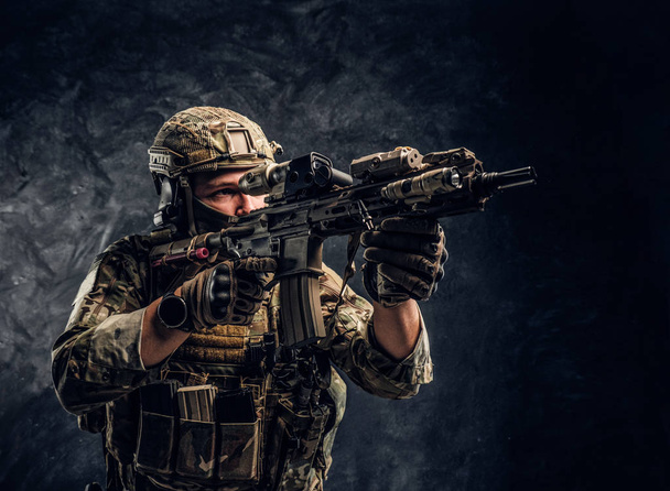 Elit birimi, Özel Kuvvetler asker bir saldırı tüfeği bir lazer görme ve amaçlar ile hedef kamuflaj üniformalı. Karanlık bir duvara Studio fotoğraf   - Fotoğraf, Görsel