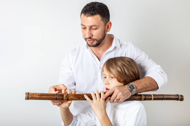 父は竹のフルートを演奏する息子を教えてください。 - 写真・画像