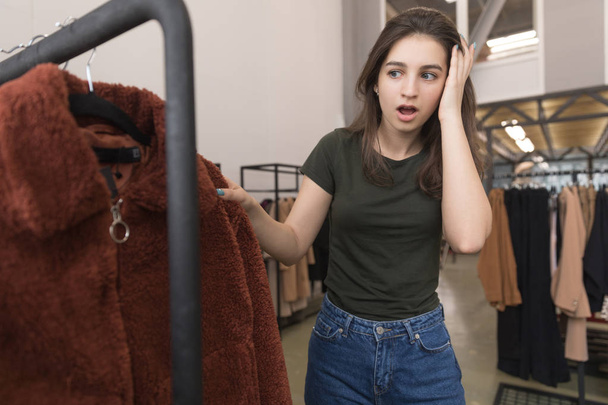 The girl in the clothing store chooses a new fur coat. - Valokuva, kuva