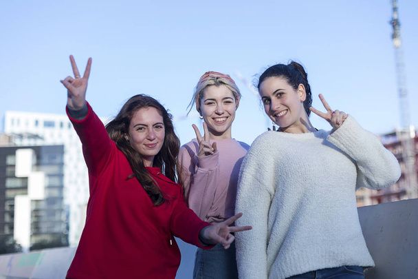 Front view of three Teenage girls making a peace sign outdoors in a sunny day - Foto, immagini