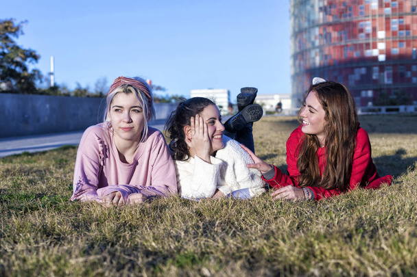 three girlfriends lying on the grass in a park in autumn - Foto, immagini