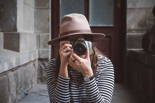 Mulher bonita nova no chapéu está tirando foto com câmera antiquada, ao ar livre
 - Foto, Imagem