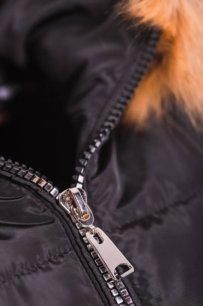 毛皮、冬ファッションの服と黒のジャケットのジッパーのクローズ アップ。白い背景で隔離のジャケット. - 写真・画像