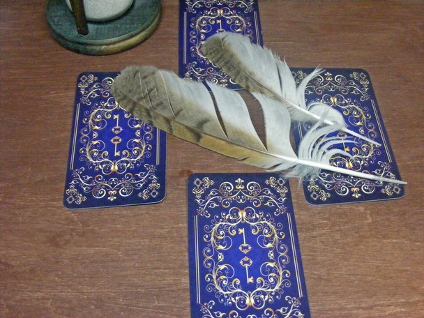 Tarot kártyák, bagoly tollak és a barna háttér homokóra - Fotó, kép