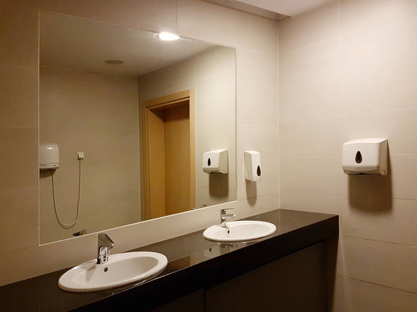 Интерьер ванной комнаты в черно-белом. Круглые керамические раковины. Зеркала, пластиковая мыльница и хромированные краны для мытья рук после туалета. Дизайн с темно облицовочной плиткой
 - Фото, изображение