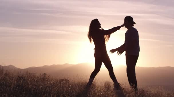 Νεαρό ερωτευμένο ζευγάρι αναπαύεται στα βουνά στο όμορφο ηλιοβασίλεμα - Πλάνα, βίντεο