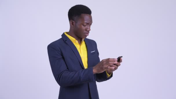 Young happy African businessman using phone and getting good news - Materiał filmowy, wideo