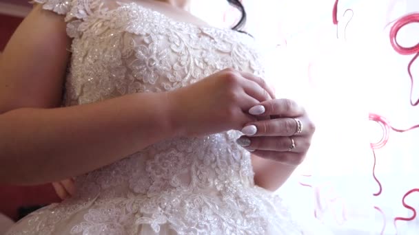 bruid is bij raam in een mooie witte bruiloft jurk, close-up permanent. mooie manicure op de handen van de bruid. bruid bereidt zich voor op de huwelijksceremonie. Bal toga naar "girl". - Video