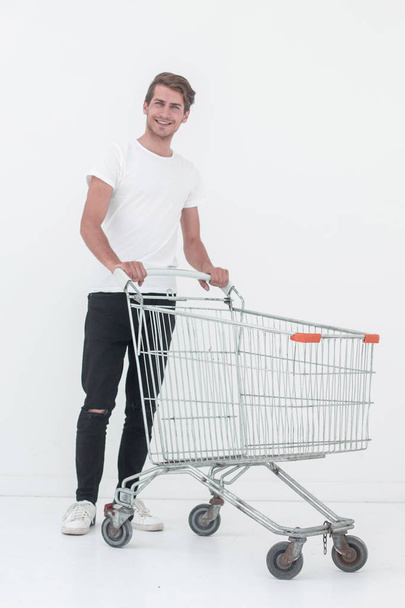 young man pushes an empty shopping cart - Valokuva, kuva