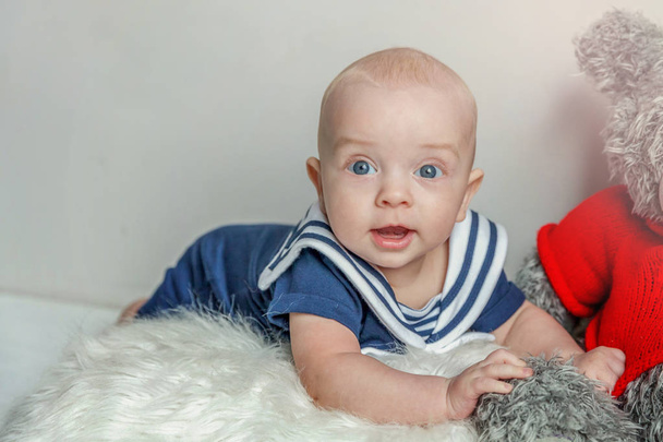 Βρέφος μωρό αγόρι βρίσκεται στο μαξιλάρι με αρκουδάκι παιχνίδι σε φόντο λευκό υπνοδωμάτιο - Φωτογραφία, εικόνα