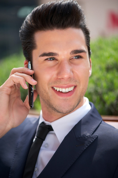Handsome young businessman talking on phone outdoors - Photo, image