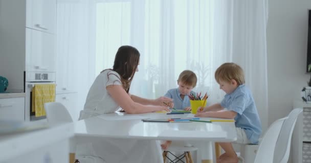 Annem ve onun iki oğlu renkli kalemler aile çimenlerin üzerine yaz aylarında çizim mutfak masasında oturuyor. Çocuklar öğrenmek çizmek ve anne çizim ile yardımcı olur. - Video, Çekim