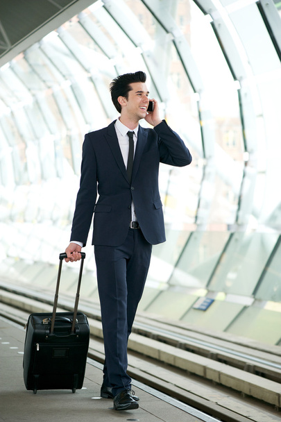 Бизнесмен, идущий по платформе вокзала и разговаривающий по телефону
 - Фото, изображение