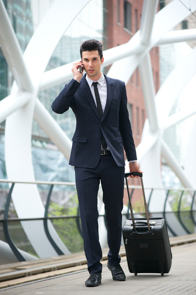 Businessman calling on phone and traveling with bag at metro station - Фото, изображение