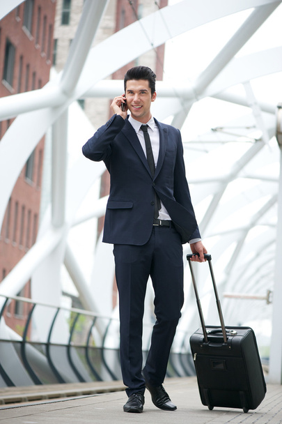 Homme d'affaires voyageant avec un sac et parlant au téléphone à la station
 - Photo, image