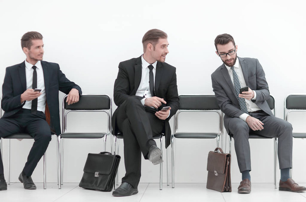 employees with smartphones sitting in the office hallway - Foto, Imagen