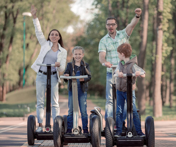 modern family riding an electric mini hoverboard in the Park - Photo, Image